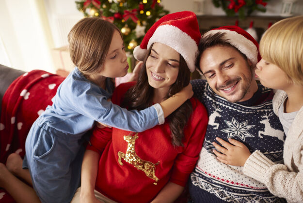 亲吻孩子们在圣诞节亲吻他们的父母孩子沙发房间
