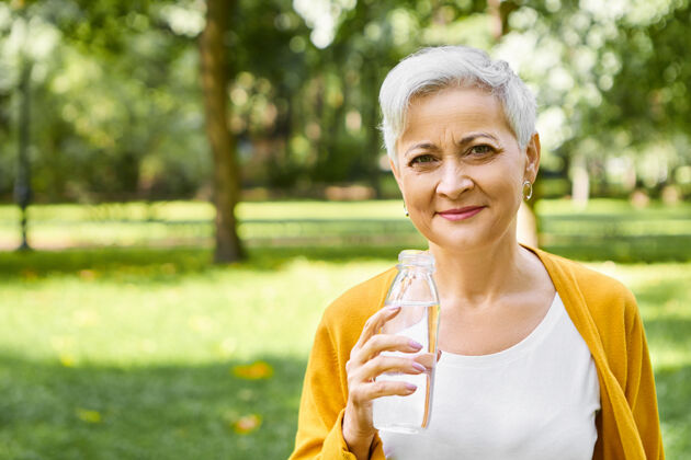 瓶子人 生活方式 健康习惯和提神理念快乐活力的欧洲老年女性的户外形象 短发手持奶瓶 在炎热的阳光下享受新鲜的饮用水公园老年人户外