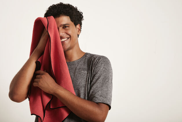 年轻年轻的黑人运动员笑着用红毛巾擦脸 右半边脸开在白色的脸上私人教练俱乐部毛巾