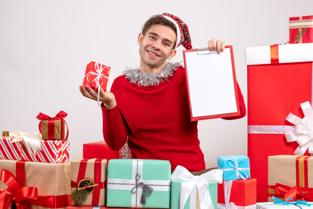 购物者前视图微笑着 戴着圣诞帽的年轻人围坐在圣诞礼物旁礼物购物圣诞老人