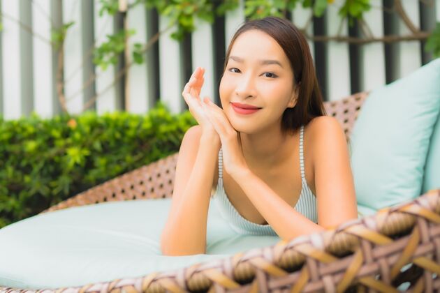 放松肖像美丽的亚洲年轻女子在酒店度假区的室外游泳池周围放松休闲旅游度假身体女人亚洲人