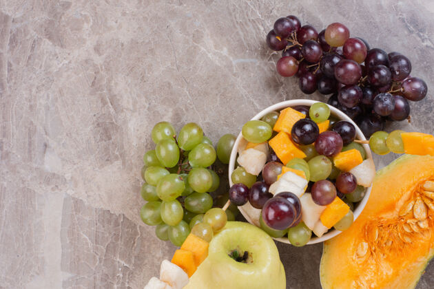 切割水果碗和新鲜水果放在大理石表面南瓜苹果水果沙拉