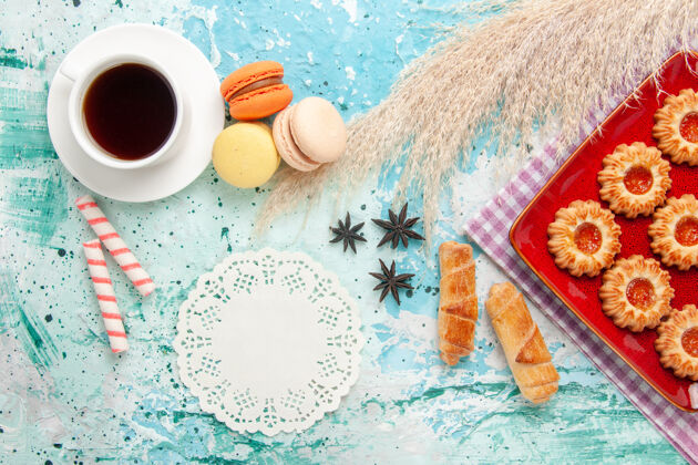 棉花顶视图甜饼与橙色果酱百吉饼和一杯茶的蓝色背景早餐百吉饼饮料