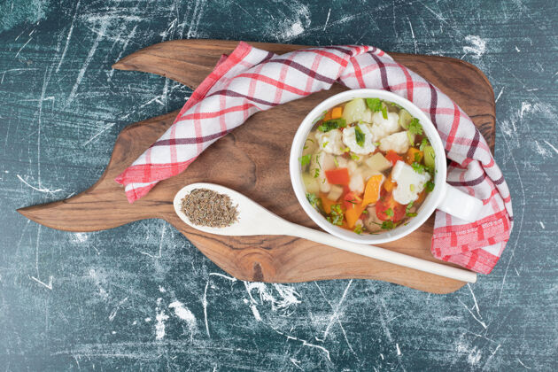 木头用勺子和桌布把蔬菜汤放在木板上食物吃的蔬菜