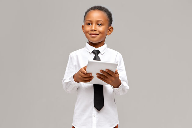 休闲儿童 电子设备和小玩意的概念聪明自信的非洲学生在制服摆姿势与便携式触摸板电脑在他手中 上网或网上购物游戏英俊学习