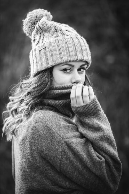 吸引人一个穿着灰色毛衣和冬季帽子的年轻白人妇女的灰度照片-冬季概念棉外观垂直
