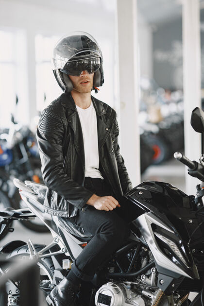 阳刚一个男人在摩托店里选摩托车一个穿黑夹克的男人一个戴头盔的男人摩托车手年轻人摩托车手