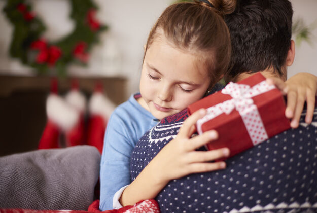 圣诞老人小女孩在圣诞节拥抱她的爸爸关闭粘合圣诞装饰品