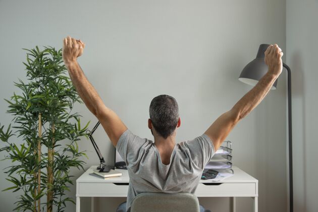 职业男人在家工作时伸展手臂的后视图远程工作职业男人