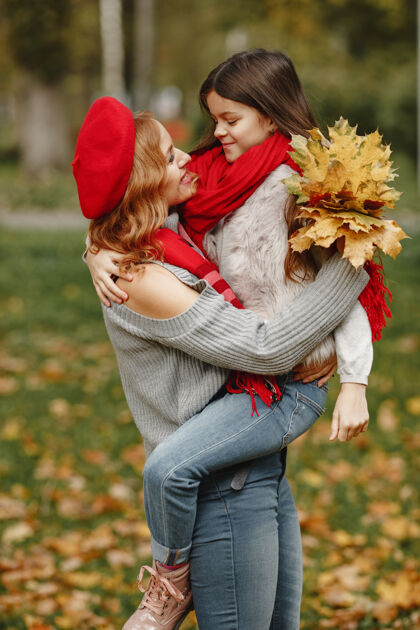 开朗时髦的母亲带着女儿黄色的秋天戴着红领巾的女人妈妈秋天衣服