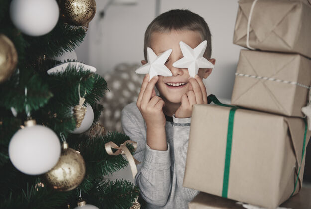 礼品盒眼前拿着圣诞装饰品的男孩举行庆祝圣诞节