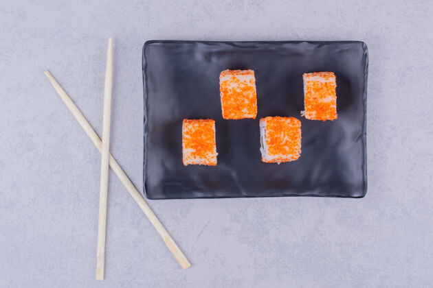 传统黑色陶瓷盘中的鲑鱼寿司卷美味午餐日本