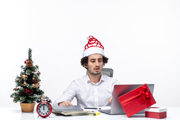 工作区戴着圣诞老人帽的年轻商人在办公室庆祝圣诞节庆祝圣诞老人圣诞树
