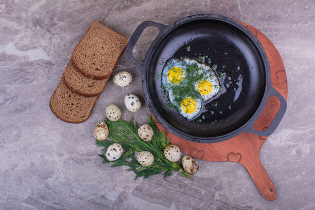 生物在金属锅里煎鸡蛋和面包片膳食烧烤早午餐