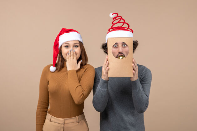 表情喜庆的心情与兴奋的酷夫妇穿着灰色的红色圣诞老人帽子圣诞老人圣诞节模型