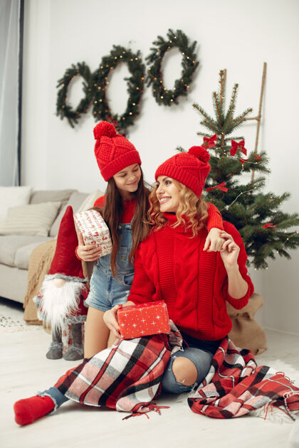 室内人们在为圣诞节做准备母亲在和女儿玩耍一家人在节日的房间里休息孩子穿着红色毛衣十二月礼物孩子