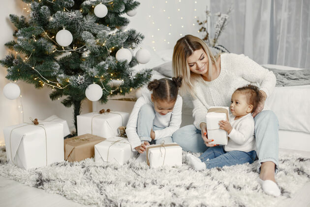 女孩人们在为圣诞节做准备母亲在和女儿们玩耍一家人在节日的房间里休息孩子穿着毛衣小女儿礼物
