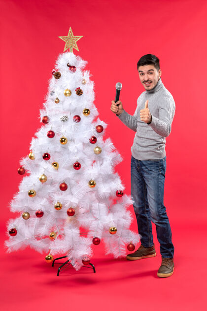 圣诞节新年气氛积极的家伙穿着牛仔裤站在装饰圣诞树附近心情礼物圣诞树