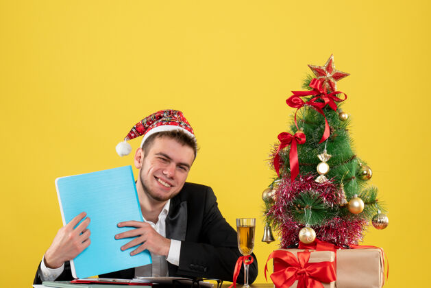 男工人正面图：男工人拿着文件围着圣诞树 在黄色的圣诞树上做礼物礼物工作圣诞树