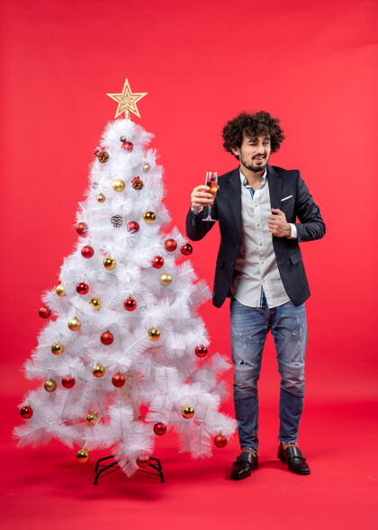 庆典圣诞节庆典上 留着胡子的年轻人拿着酒站在圣诞树旁说些什么站着树肖像