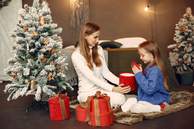 花环人们在为圣诞节做准备母亲在和女儿玩耍一家人在节日的房间里休息孩子穿着蓝色毛衣杉木礼物女人
