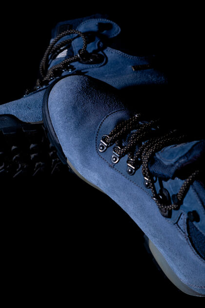 鞋子黑色背景的蓝色冬季长途跋涉靴的垂直拍摄蓝色脚徒步旅行