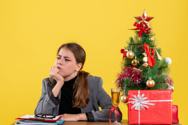 礼物前视图思维可爱的女孩坐在办公桌圣诞树和礼物鸡尾酒可爱的女孩桌子电话