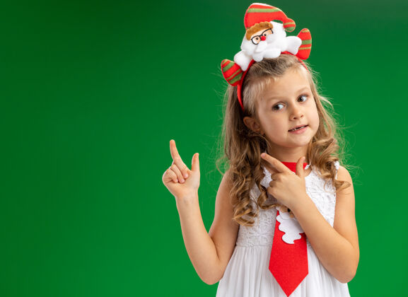 领带令人印象深刻的小女孩戴着圣诞发箍与领带点在后面孤立的绿色墙壁与复制空间小印象深刻分
