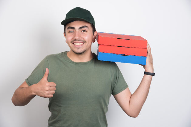制服送货员拿着三盒披萨 在白色背景上竖起大拇指披萨送货思考