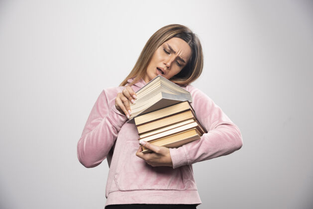 成人一个穿着粉色衬衫的女孩手里拿着一堆书 打开上面的一本读着重型人服装