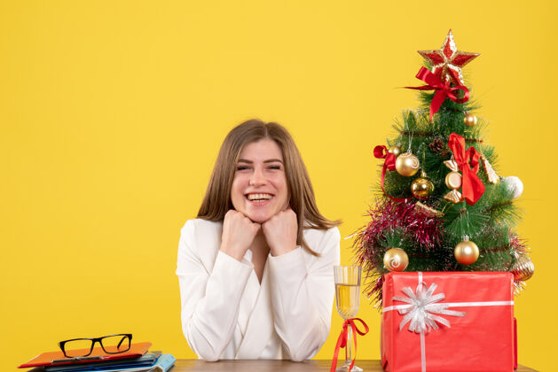 人正面图：女医生坐在黄色背景的桌子前 放着圣诞树和礼品盒办公室医院人