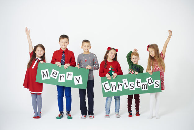 节日快乐的孩子们拿着圣诞装饰品标语牌活动孩子