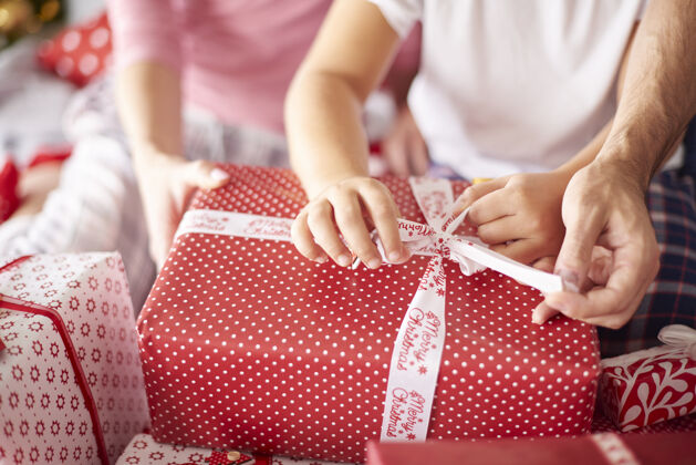 包装打开圣诞礼物时家庭手的特写镜头向上孩子礼物