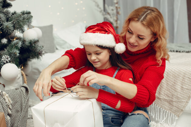 礼物人们在为圣诞节做准备母亲在和女儿玩耍一家人在节日的房间里休息孩子穿着红色毛衣家家庭杉木