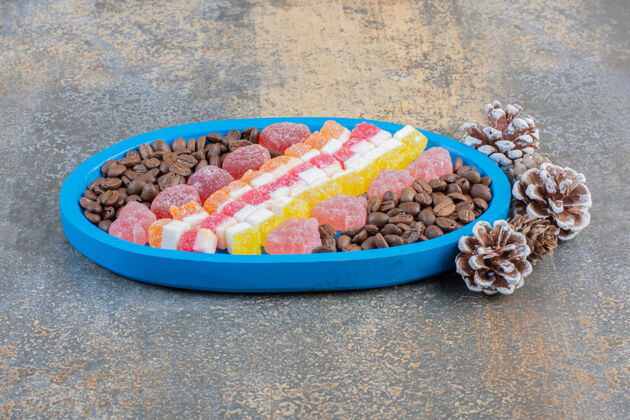 节日一个蓝色的板上装满了不同的果冻糖果和松果高质量的照片糖糖果水果