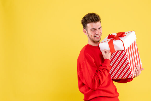 红色正面图：穿着红色衬衫的年轻男性 带着圣诞礼物雪圣诞节礼物