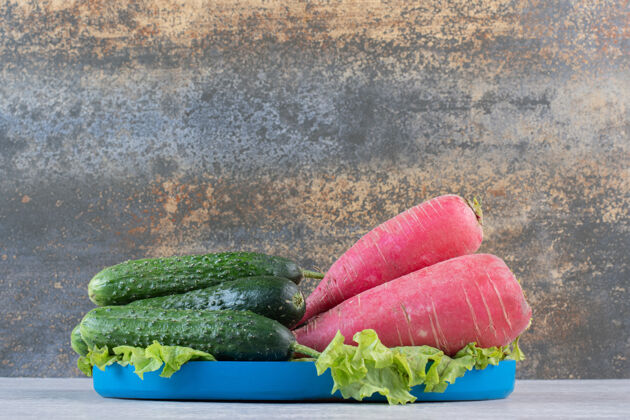 生菜健康的黄瓜和红萝卜放在蓝色的盘子里高质量的照片天然有机叶