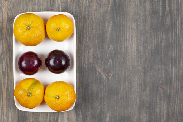 生的木桌上的甜橘子和李子高质量的照片异国情调李子柑橘