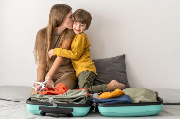 亲吻妈妈和孩子带着行李在家飞机航行旅行