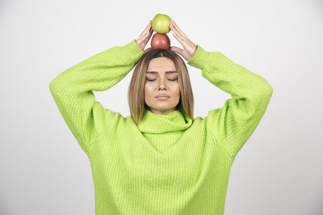成人身穿绿色t恤的年轻女子头顶举着两个苹果用餐人营养