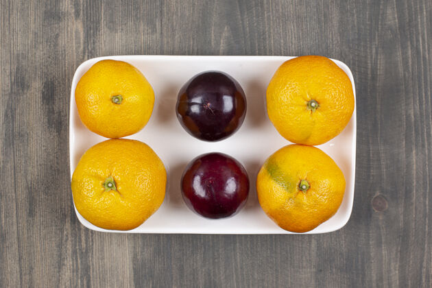水果木桌上的甜橘子和李子高质量的照片多汁成熟柑橘