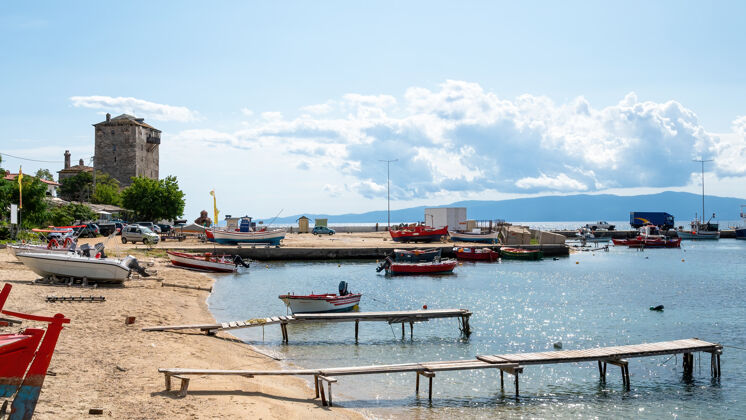 地标海港 停泊在爱琴海上的船只 停着的汽车很少 两个小木墩和prosphorion塔 ouranoupolis 希腊海滩渔业景观