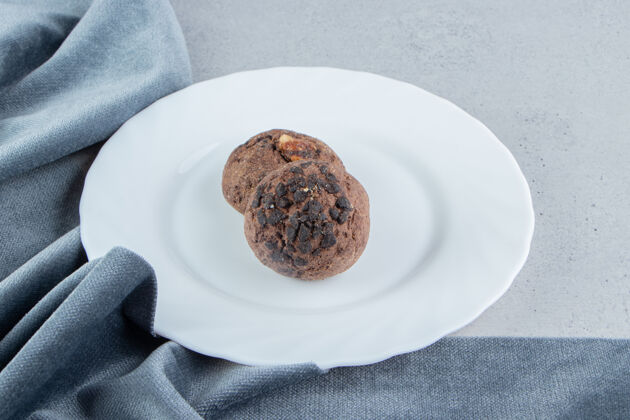 薯片巧克力饼干放在白色盘子里 靠近大理石背景上的桌布桌布饼干美味