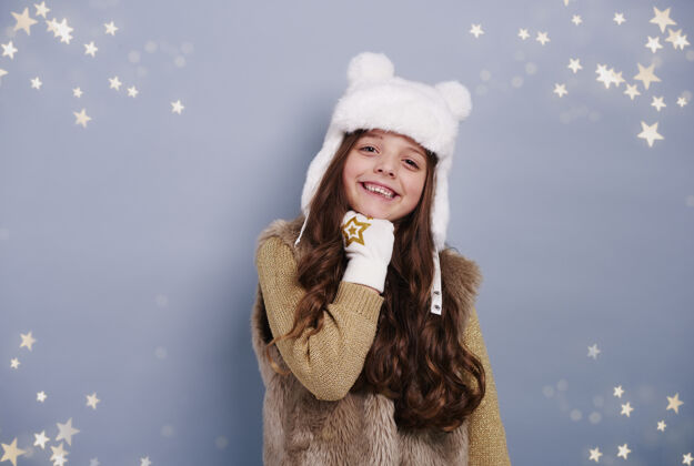 季节戴着冬天帽子和手套的女孩圣诞节牙齿的微笑摆姿势