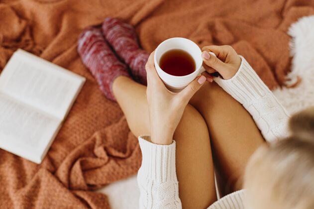 放松高角度的年轻女子端着一杯茶舒适季节性季节