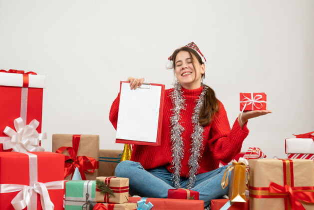 圣诞老人戴着圣诞帽的快乐女孩闭上眼睛拿着礼物围坐在白色的礼物上眼睛礼物快乐女孩