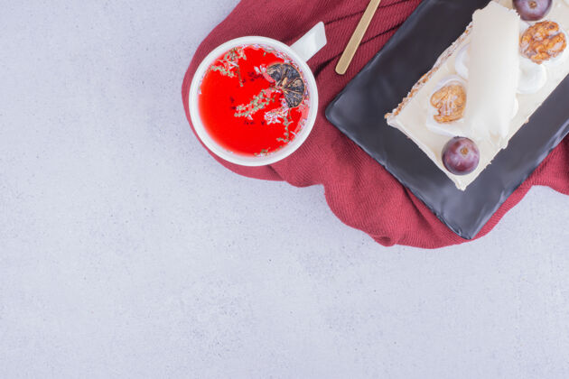咖啡馆一片蛋糕放在一个陶瓷盘子里 再加一杯红色的花草茶甜点奶油小吃