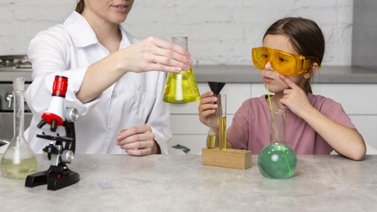 检查女教师和女孩用试管和显微镜做科学实验科学家女性化学