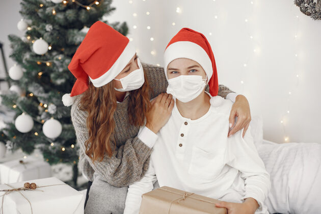 内饰为圣诞节做准备的人冠状病毒主题妈妈和儿子玩穿白毛衣的男孩冠状病毒小母亲