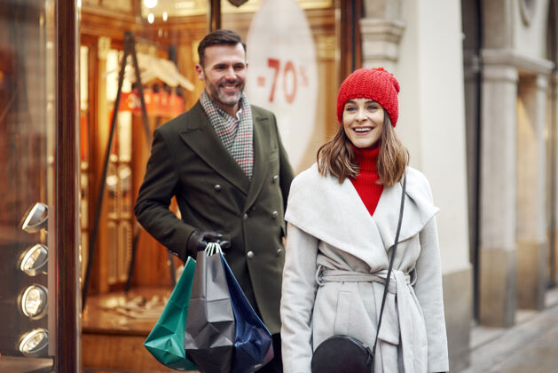 街道愉快的情侣在冬季购物美丽的人优雅女人